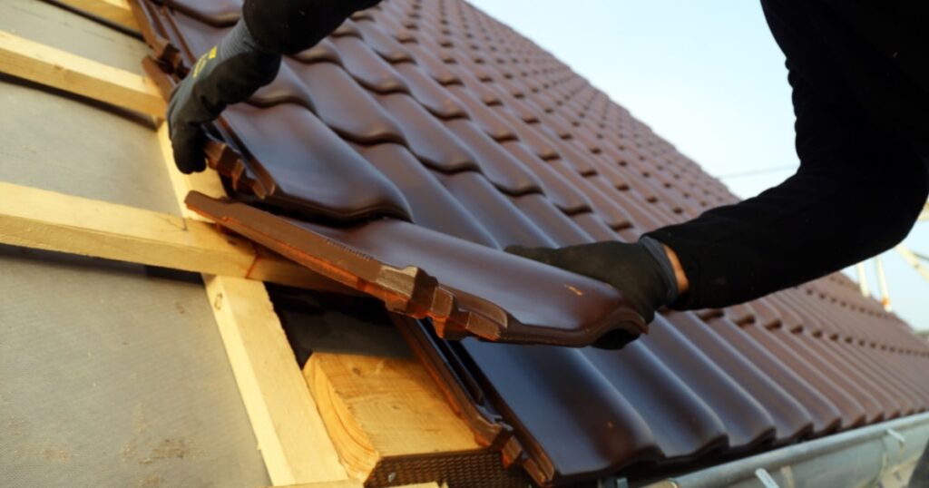 Un couvreur installe une toiture en tuiles à emboitement. 