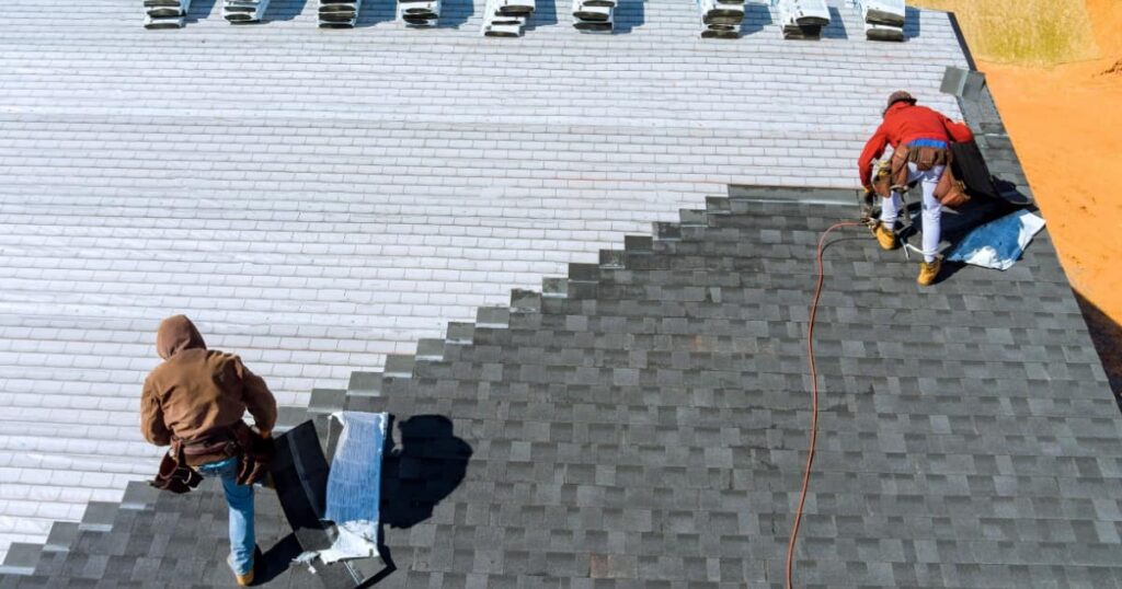 Deux experts rénovant une toiture avec des plaques de shingle