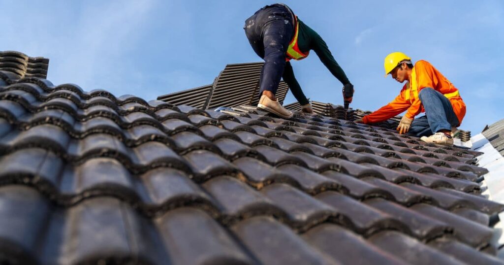 deux hommes travaillant sur un toit en tuile 