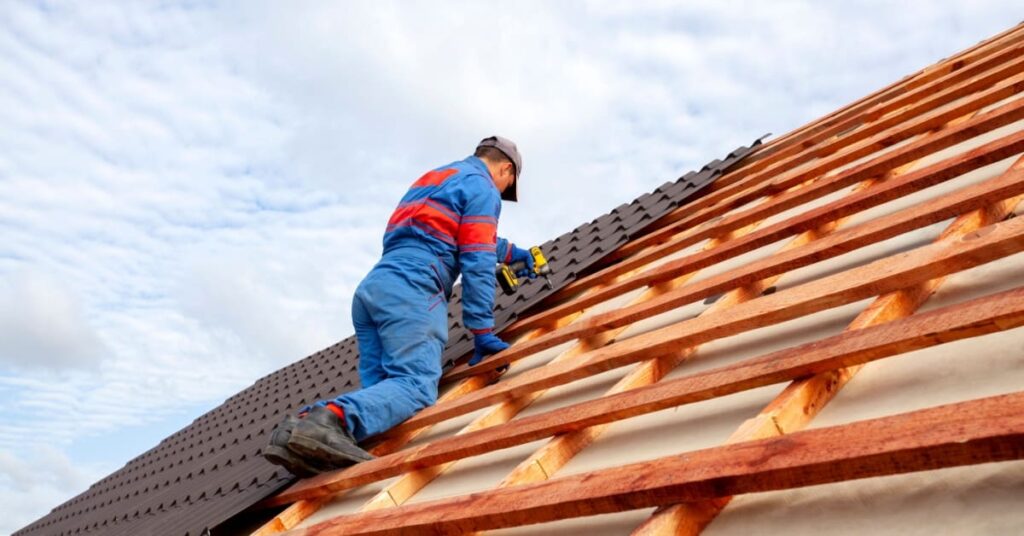 homme qui pose tuiles sur toit maison